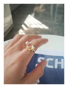 Gros plan d'une bague dorée minimaliste avec perle et détail de pétale métallique