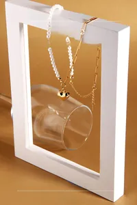 Detail of a pearl and gold clip chain necklace with a polished gold heart pendant