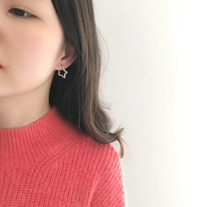 Detailed view of silver star stud earring with hammer texture on a model wearing orange