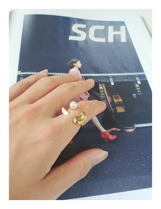 Vue détaillée d'une bague ajustable dorée avec perle blanche et design en métal irrégulier