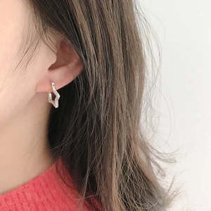 Detailed view of silver star-shaped earring with zircon pavé worn on earlobe