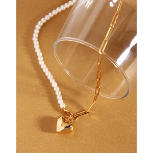 Detail of half-pearl half-chain necklace with a polished gold heart pendant and paperclip link