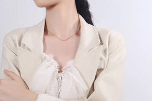 Detailed view of a minimalist gold collarbone chain necklace worn on a model in a suit