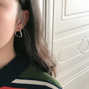 Close-up of model wearing geometric silver triangular earrings with polished finish