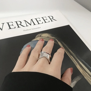 Close-up of a wide concave silver ring with a minimalist irregular design on a hand