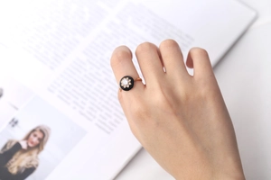 Detail of s925 gold-plated ring with black enamel and sparkling floral diamond center