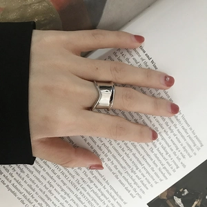 Close-up of minimalist irregular wide silver ring worn on index finger with art book