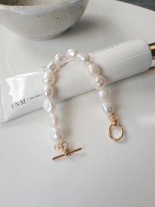 Detailed close-up of baroque pearl bracelet featuring a decorative golden OT buckle clasp