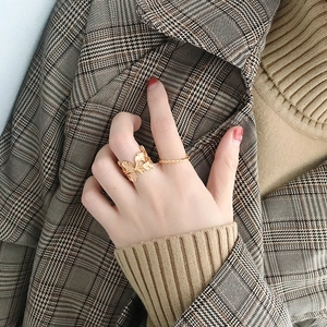Close-up of golden ginkgo leaf and twisted rope rings worn with autumn coat