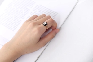 Detail of S925 silver gold ring with black enamel flower and cubic zirconia on model hand
