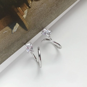 Macro shot of S-shaped silver stud earrings with rectangle-cut zircon stones