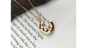 Detailed close-up of a crescent-shaped gold pendant with a pearl inlay on a fine chain