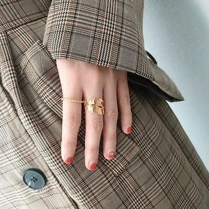 Close-up of a gold ginkgo leaf open ring and twisted rope band worn on a model's finger