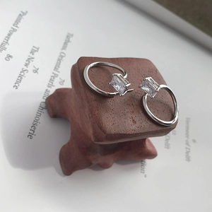 Detailed close-up of S925 sterling silver earrings with square zircon on wooden stand