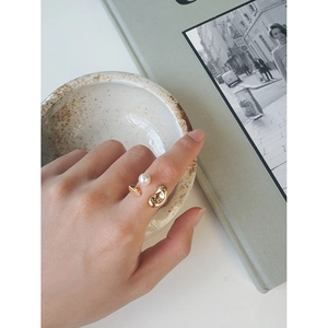 Bague ouverte dorée minimaliste avec perle blanche portée sur la main d'un modèle