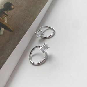 Macro detail of S925 sterling silver earrings with rectangular zirconia stones on books
