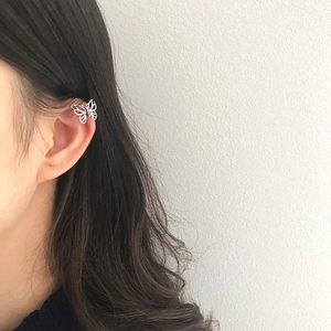 Close-up of a silver hollow butterfly ear cuff worn on a model's ear, sleek and minimal