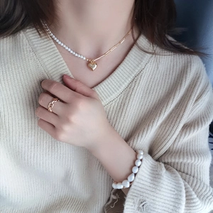Baroque pearl bracelet and heart pendant necklace set with golden ring on a model
