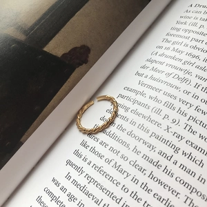 Close-up of golden S925 sterling silver twisted rope ring on an open book page