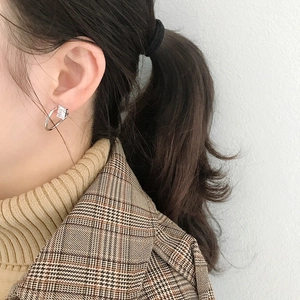 Detail view of silver geometric earring with rectangular zircon on model wearing a blazer