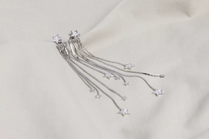 Detail of silver S925 star tassel earrings with crystal fringe on soft white fabric