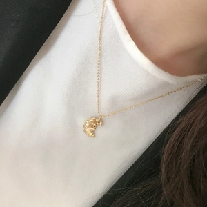Detail of a golden croissant crescent pendant with a textured finish on a chain