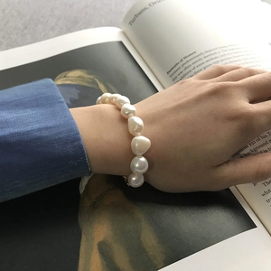 Close-up of irregular Baroque pearl bracelet on wrist with elegant artistic background