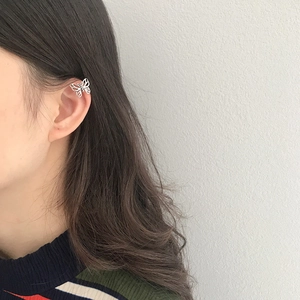 Close-up of a minimalist hollow butterfly ear cuff worn on the ear bone by a female model