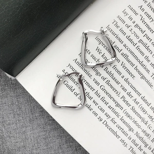 Close-up of geometric twisted silver earrings with a mirror polished finish on an art book