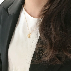 Close-up of golden ginkgo leaf pendant with delicate radial texture on a silver chain