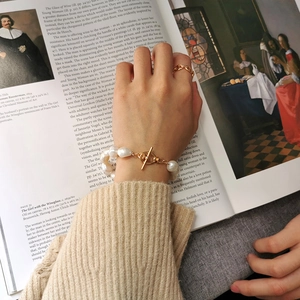 Detail of baroque pearl bracelet with gold T-bar clasp against a vintage art book