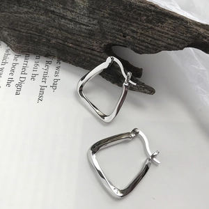Detail view of geometric S925 sterling silver earrings on a minimalist book background