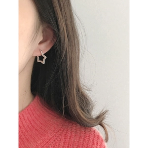 Minimalist silver star stud earrings with pavé zircon stones worn on ear
