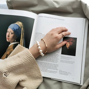 Baroque pearl bracelet and gold bamboo bangle styled on a classic art book background