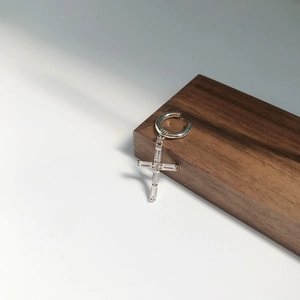 Detailed view of S925 sterling silver ear cuff featuring a zircon cross on dark wood