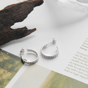 Detailed macro of S925 sterling silver hoop earrings with unique scalloped edge design