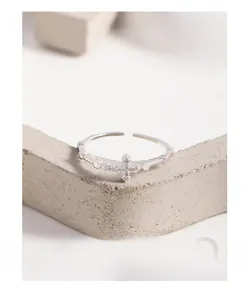 Détail macro d'une bague croix en argent S925 sertie de zircons sur un support en pierre