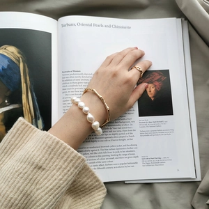Close-up of baroque pearl bracelet and bamboo bangle on art book background