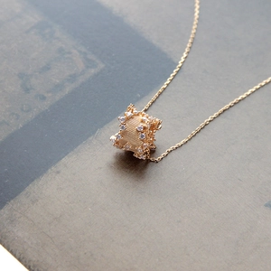 Close-up of gold S925 silver cylinder pendant with vertical stripes and small white zircons