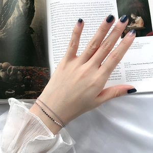 Elegant silver layered bracelet with delicate beads worn on wrist with silk background