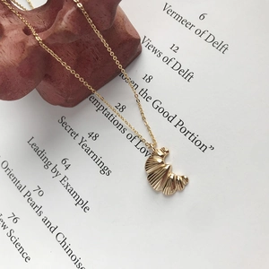 Detail of a gold croissant pendant necklace with spiral texture on a vintage book page