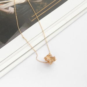Detailed view of a gold geometric cube pendant encrusted with pavé cubic zirconia