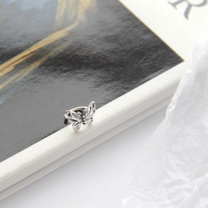 Detailed view of silver butterfly ear cuff with vintage filigree texture on a book