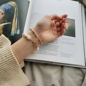 Baroque pearl bracelet and golden bamboo bangle styled with classic oil painting background