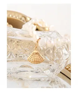 Vue détaillée de perles blanches lustrées avec un pendentif en métal doré en forme d'éventail