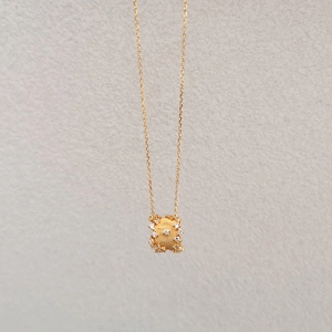 Detailed view of golden cylinder pendant with brushed metal texture and sparkling zircon stones