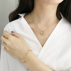 Détail d'un ensemble de bijoux dorés avec pendentif soleil et fermoir en T élégant