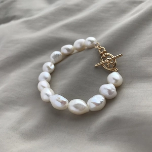 Macro detail of natural Baroque pearls with golden OT clasp on soft fabric background