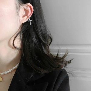Macro detail of silver cross ear cuff with clear cubic zirconia on female model