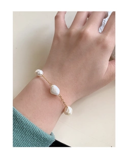 Close-up of minimalist gold chain bracelet featuring three baroque pearls on a wrist
